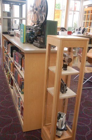 photo of display of antique movie projector and hand held movie cameras.