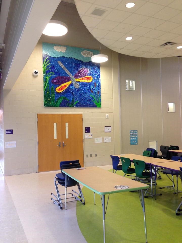 photo of cafeteria displaying dragonfly artwork made completely of drink plastic caps.