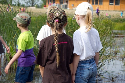 students standing along the water pond looking at water