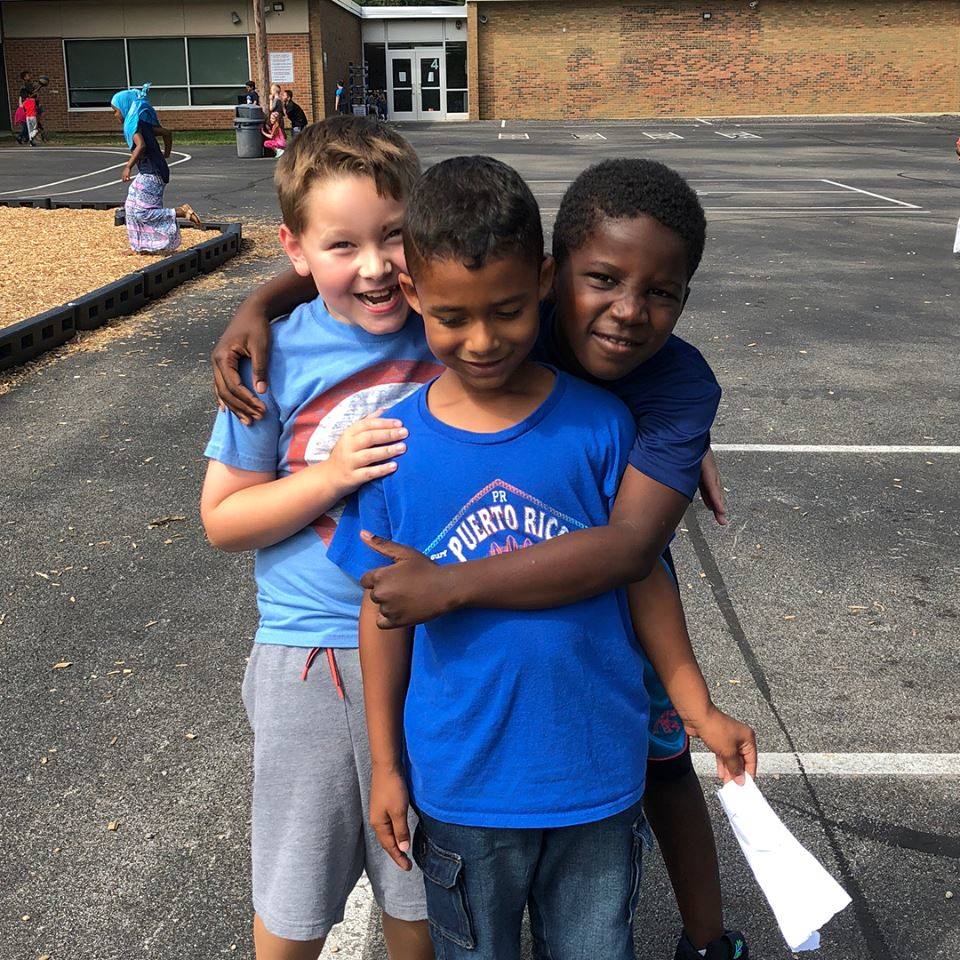 Three boys hugging at recess
