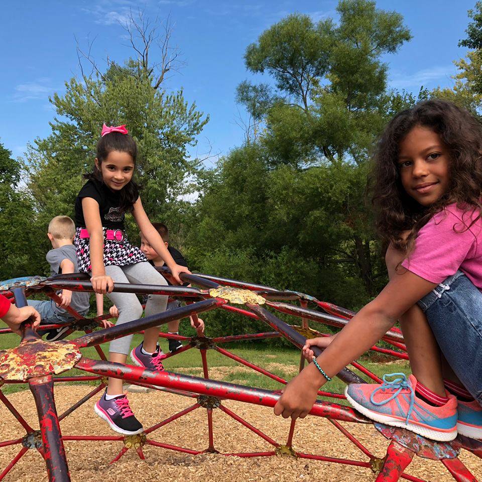 Two girls at recess, playing on a jungle jim