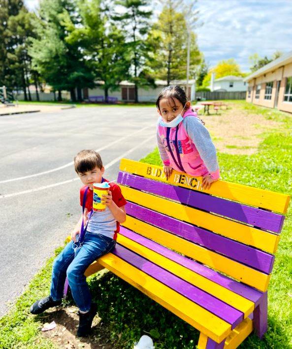 Rose Hill Students sitting on a bench painted with the school colors