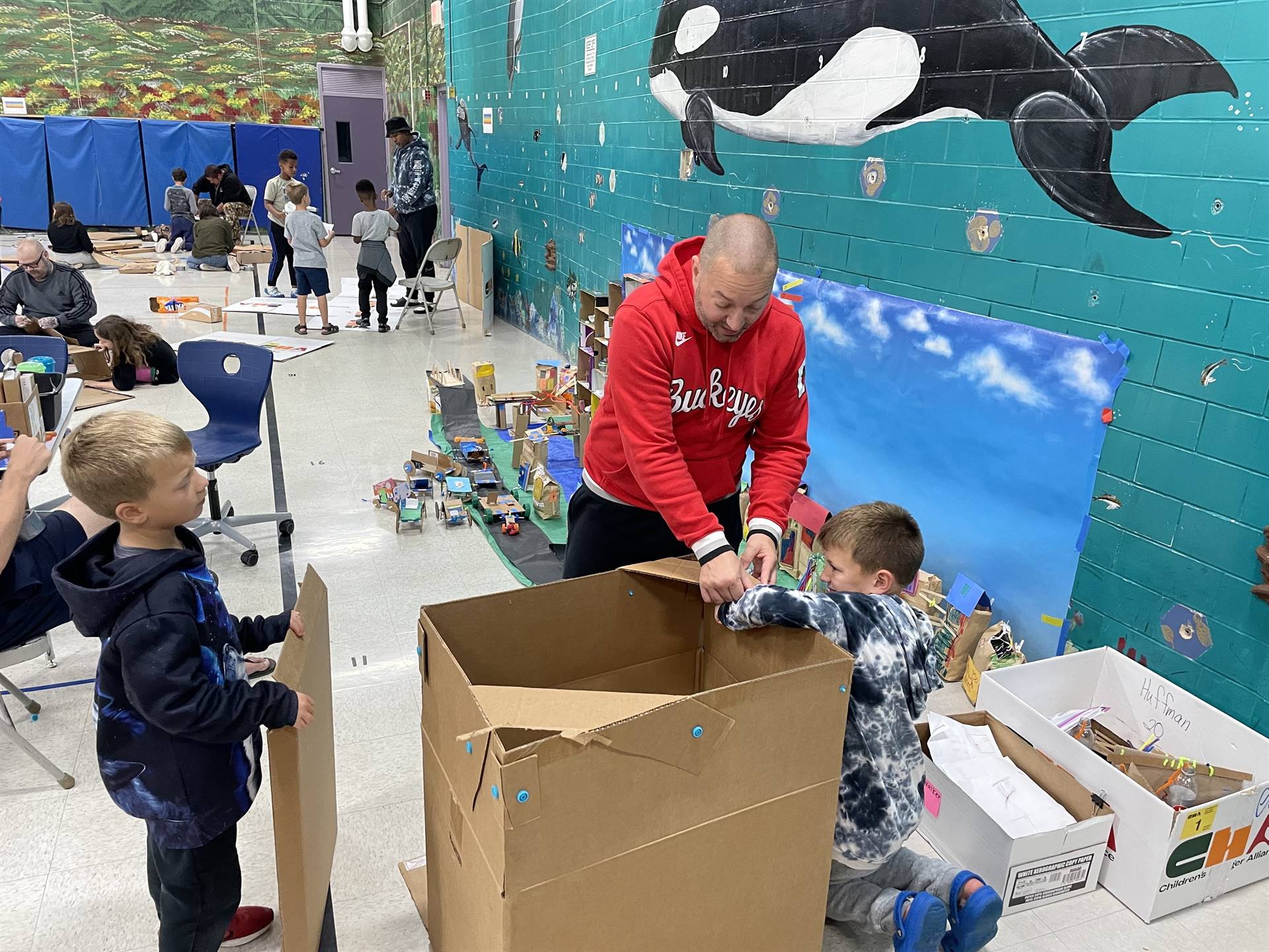 Firebird families in the gymnasium build with cardboard. 