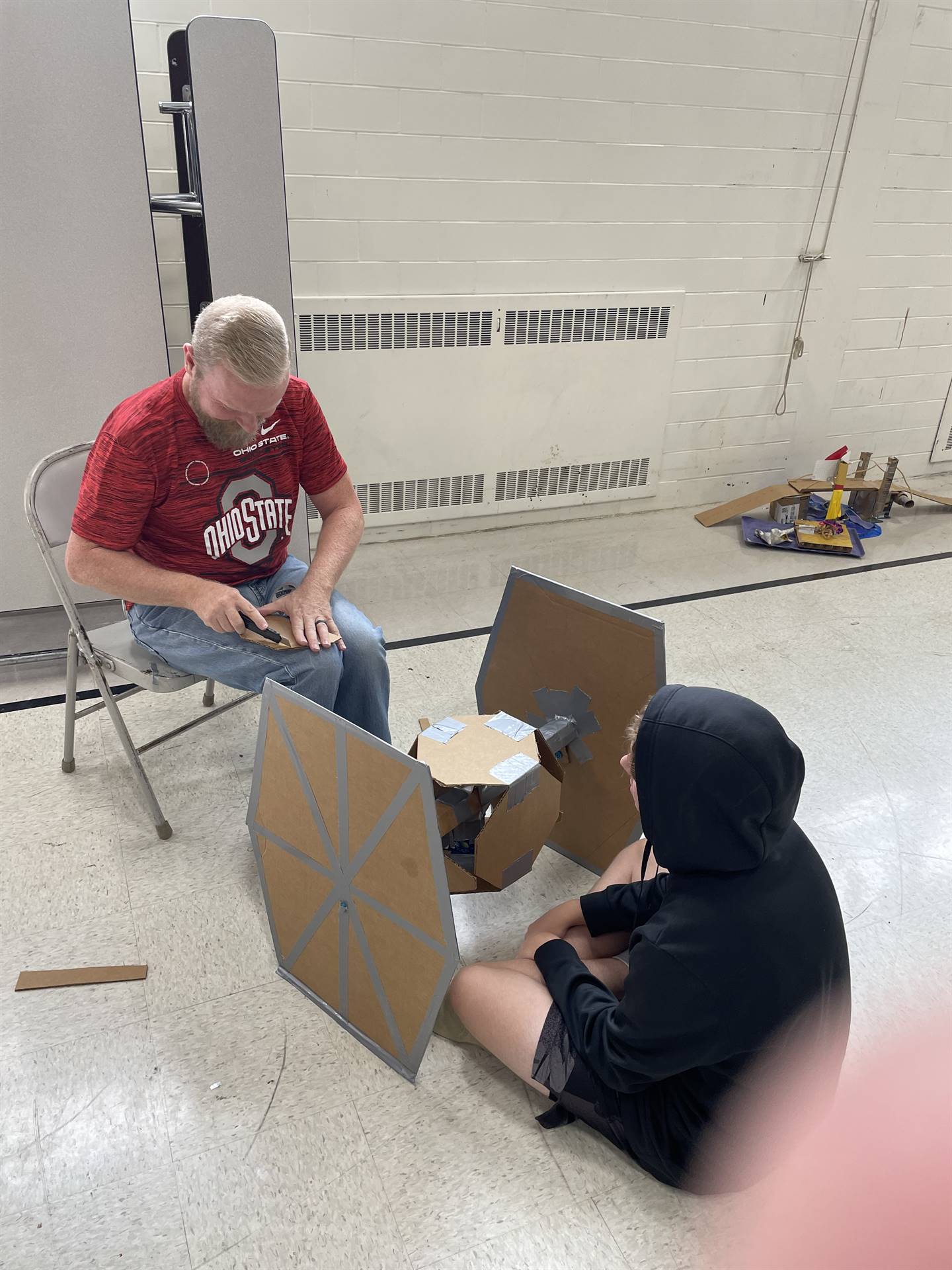 Firebird families in the gymnasium build with cardboard. 