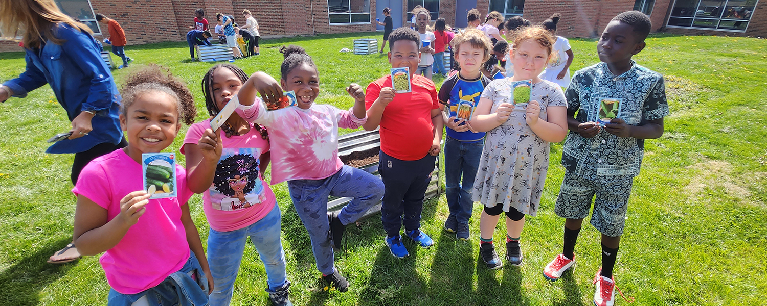 Herbert Mills STEAM Elementary students hold seed packets in the school&#39;s outdoor garden