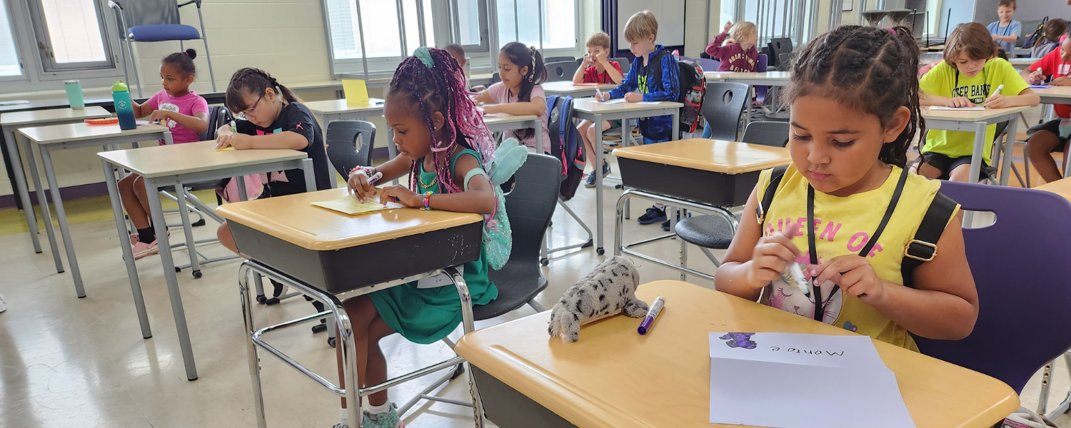 Students attending ReynExpressions Summer Camp sit at desks in the classroom to draw 