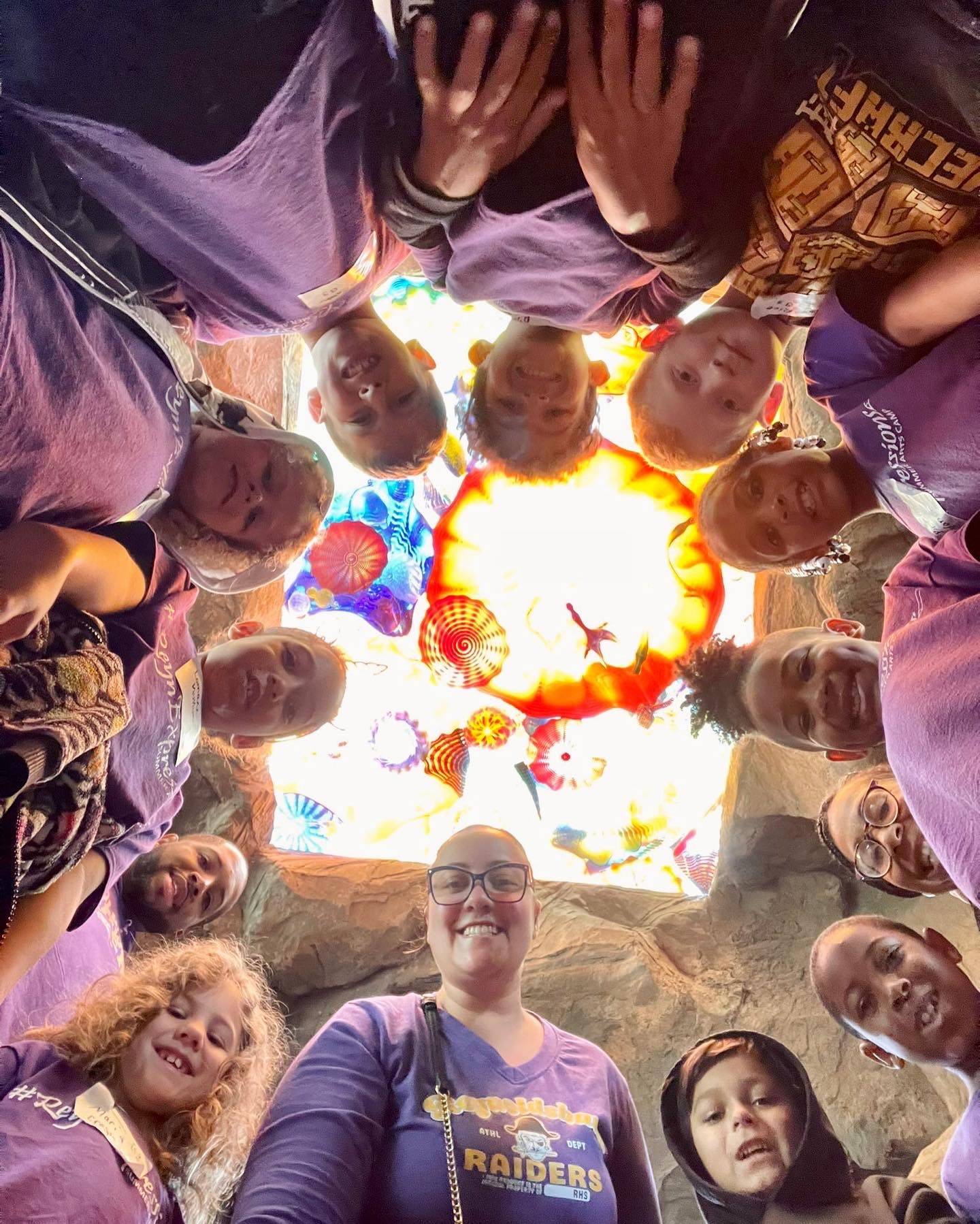 Students in a circle look down at the camera