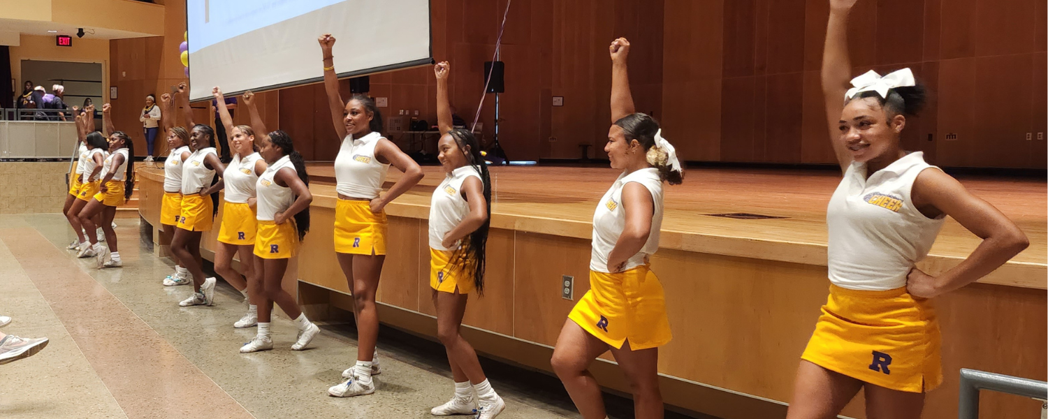 High school cheerleaders stand in a line during a cheer