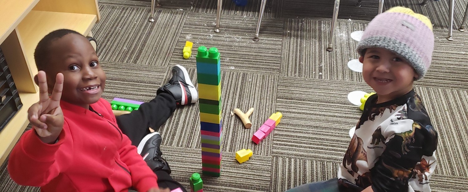 Preschool students playing with blocks and smiling