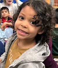Preschool girl with brown eyes and hair smiling at the camera