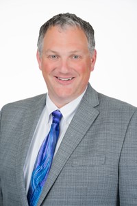 Principal Jason Phillips wearing a grey suit and blue tie