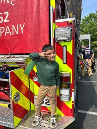 Preschool boy standing on the back of the fire truck